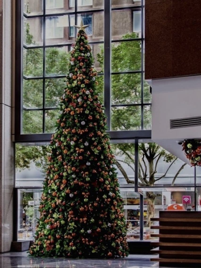 Hoge kunstkerstboom in een lichte hal met een glazen gevel