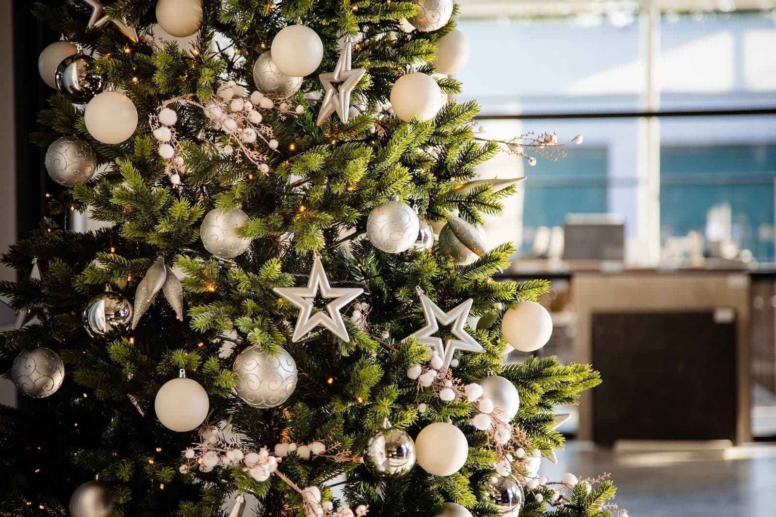 Kunstkerstboom met zilveren en witte kerstballen in een kantoorruimte