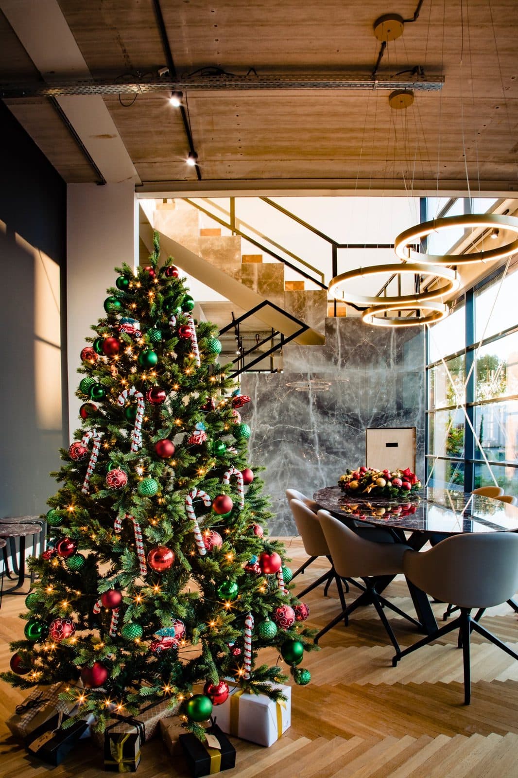 Versierde kunstkerstboom met rode en groene kerstballen in een modern restaurant