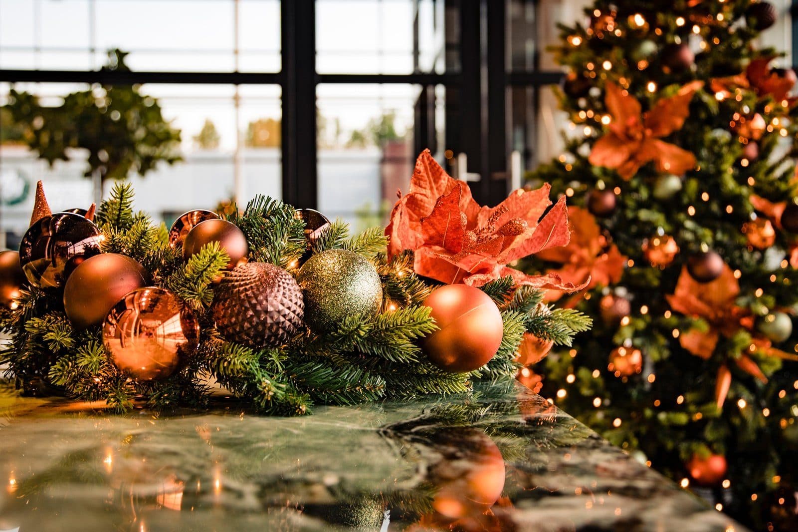 Tafeldecoratie met koperen en amberkleurige kerstballen op een bar
